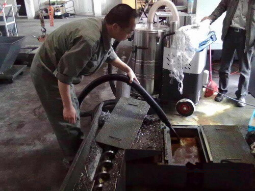工人正在用工厂吸铁屑吸尘器吸车床的铁屑